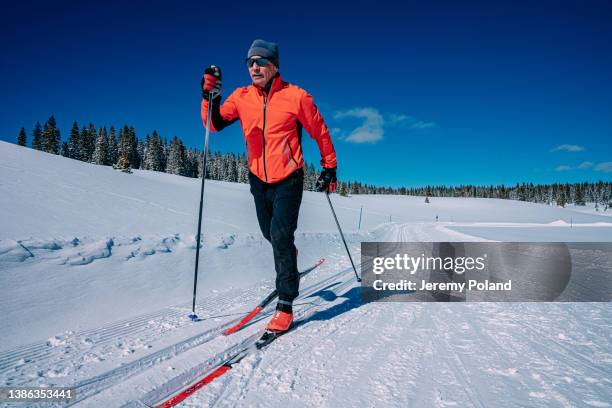 close-up low wide angle shot of a cross-country skier skiing in a diagonal stride along a groomed trail on a clear, sunny "blue bird" day in the grand mesa national forest in colorado - man skiing stock pictures, royalty-free photos & images