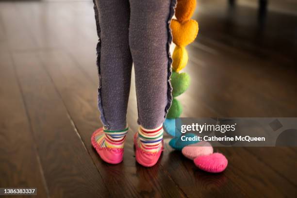 young girl carries vibrant multicolor heart felt string garland at home - play date ストックフォトと画像
