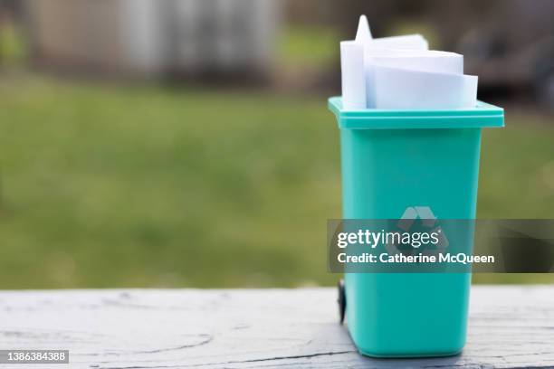 plastic toy recycling container with recycling symbol filled with white paper on outdoor ledge - prullenbak op wielen stockfoto's en -beelden