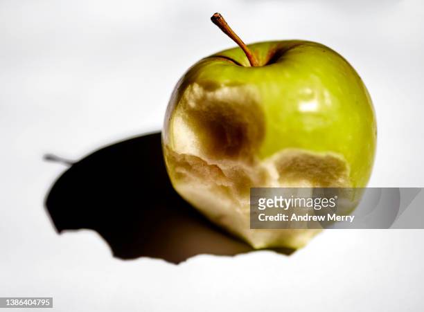 old brown apple, part eaten, stem, gray background, close up - social bite stock pictures, royalty-free photos & images