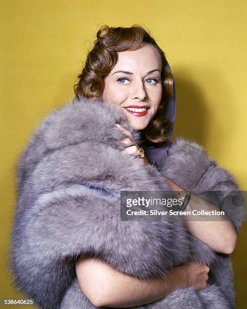 Paulette Goddard , US actress, wrapped in a grey fur stole, in a studio portrait, against a yellow background, circa 1945.