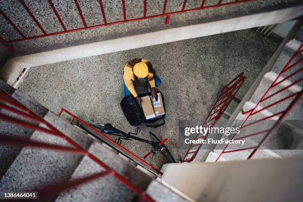 funcionária dos correios, descarregando pacotes da mochila de entrega, no prédio - carteiro - fotografias e filmes do acervo