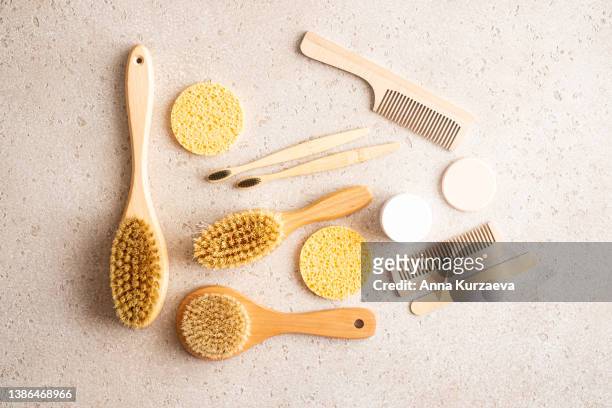 close-up of wooden dry skin body brushes, bamboo tooth brushes, hair brushes, nail brush, cotton swabs and pads on concrete background, top view. spa at home, flat lay. zero waste concept. knolling concept - dry hair photos et images de collection