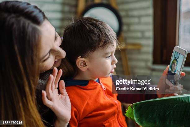 mother helping her son with his hearing aid - hearing aids stock pictures, royalty-free photos & images