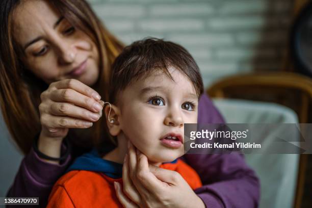 mother helping her son with his hearing aid - special needs children stock pictures, royalty-free photos & images