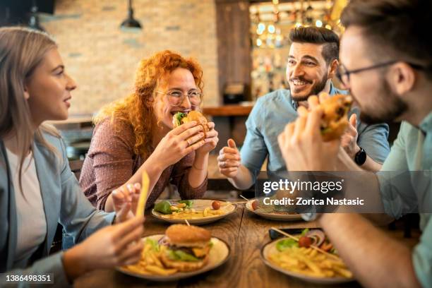 friends eating together - eating burger stock pictures, royalty-free photos & images