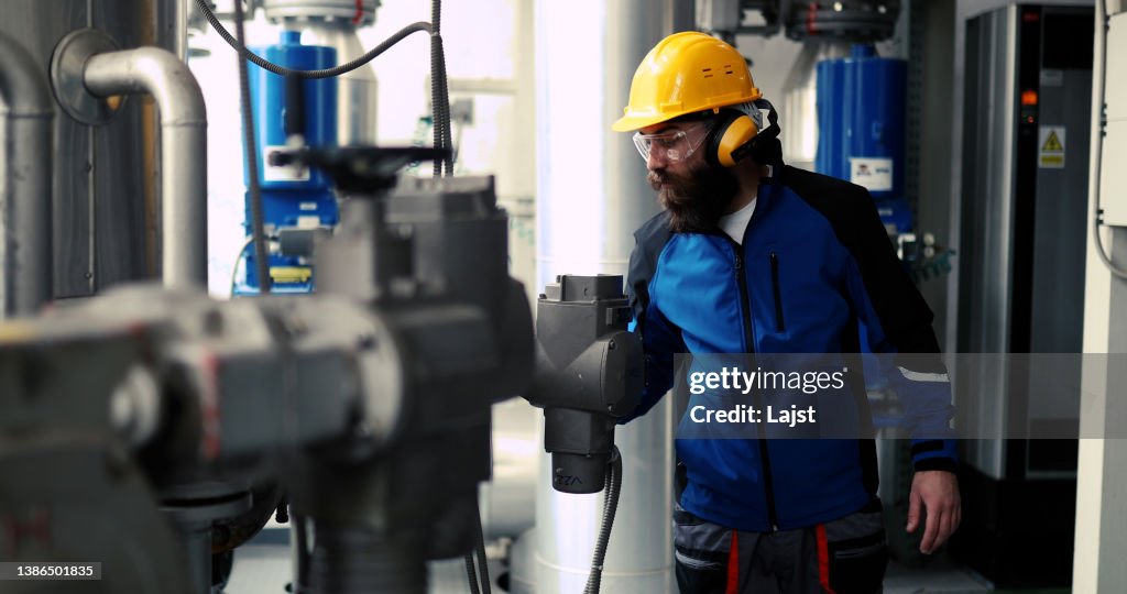 Ein Arbeiter mit Antiphonen arbeitet in einem Heizwerk.