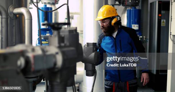 ein arbeiter mit antiphonen arbeitet in einem heizwerk. - oil and gas workers stock-fotos und bilder