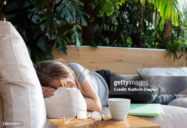 woman napping on the sofa, laptop beside her - woman 45 sleeping stock pictures, royalty-free photos & images