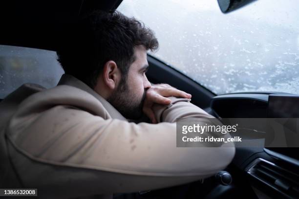 mürrischer junger mann im auto - müdigkeit winter stock-fotos und bilder