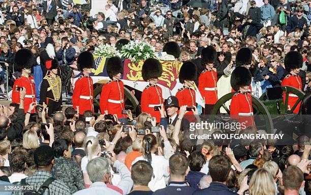 Guardsmen escort the coffin of Diana, Princess of Wales draped in the Royal Standard, as the cortege passes through crowds gathered outside...