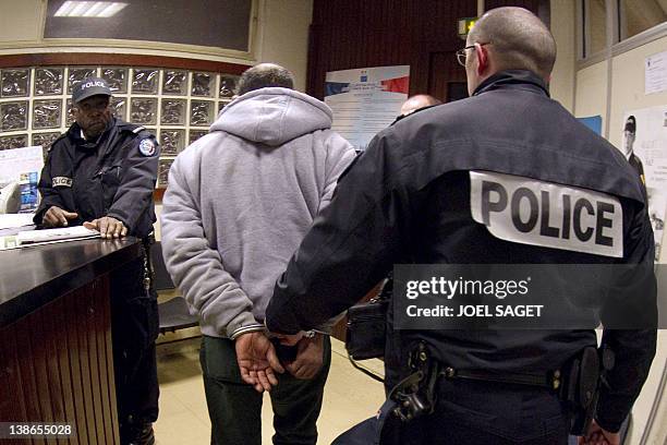 Man arrives handcuffed after being arrested by policemen, at a parisian police station, on February 09, 2012. AFP PHOTO / JOEL SAGET