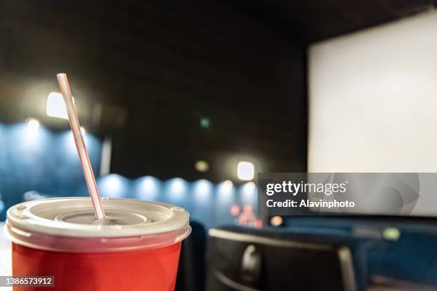 close-up of red drink with straw with seats in the background in the cinema theater - contemporary documentaries stock pictures, royalty-free photos & images