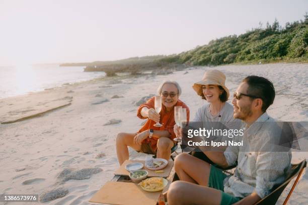 family having a toast on beach, japan - candid beach stock-fotos und bilder