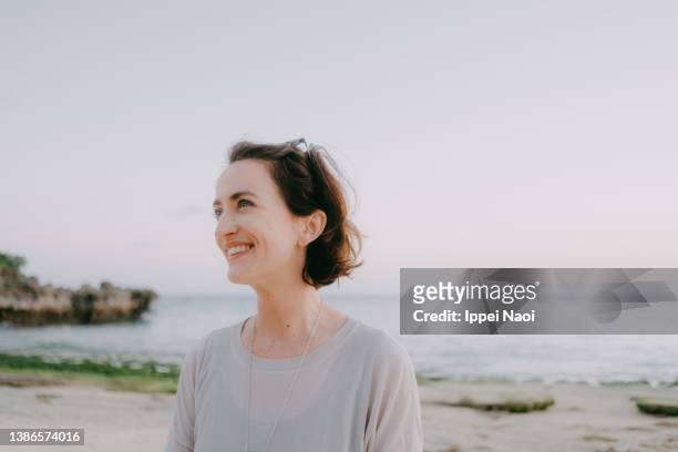 portrait of woman smiling on beach at sunset - season 42 stock pictures, royalty-free photos & images