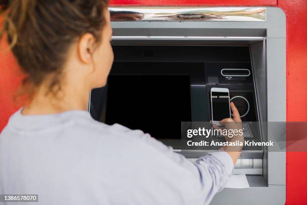 close-up of the use of a smartphone with contactless technology at an atm. - computer screen close up stock pictures, royalty-free photos & images