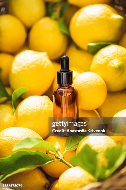 lemon essential aroma oil extract in amber dropper glass bottle lying on fresh lemons. - aromatherapy oil stock pictures, royalty-free photos & images