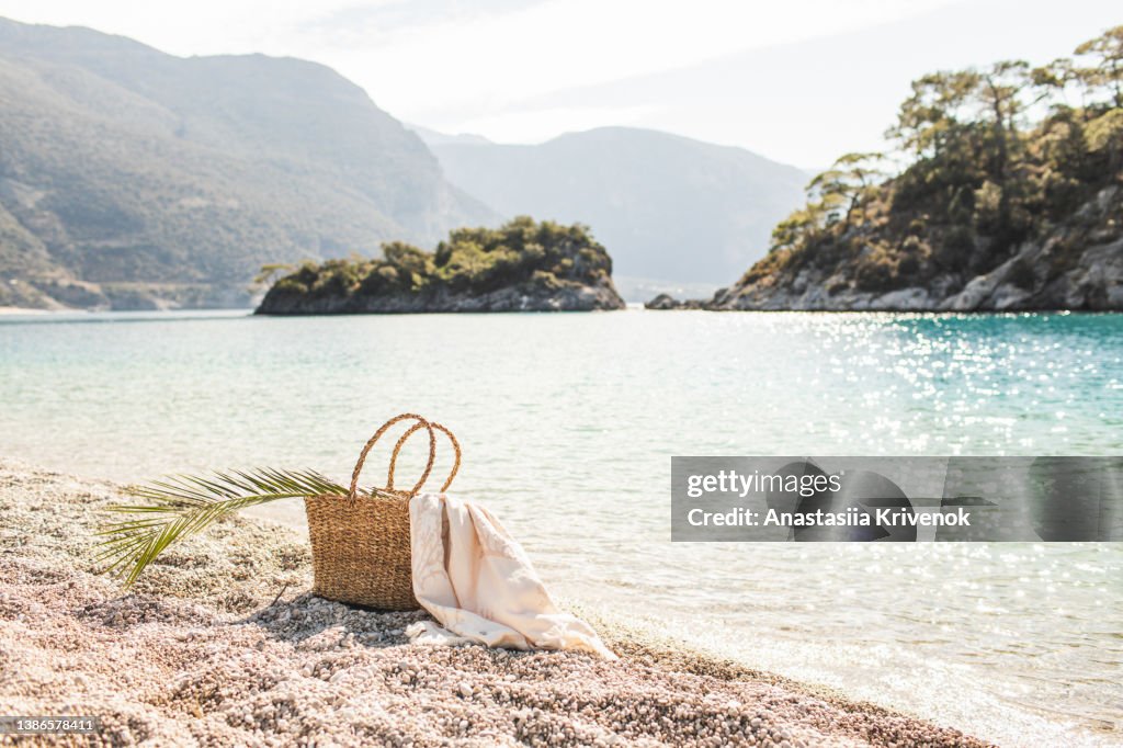 Straw beach bag on sandy beach.
