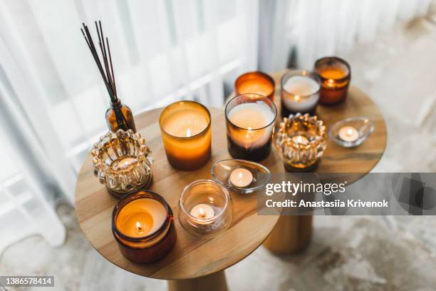 scented candles in different candlelights on wooden table at home. - kaarsen stockfoto's en -beelden