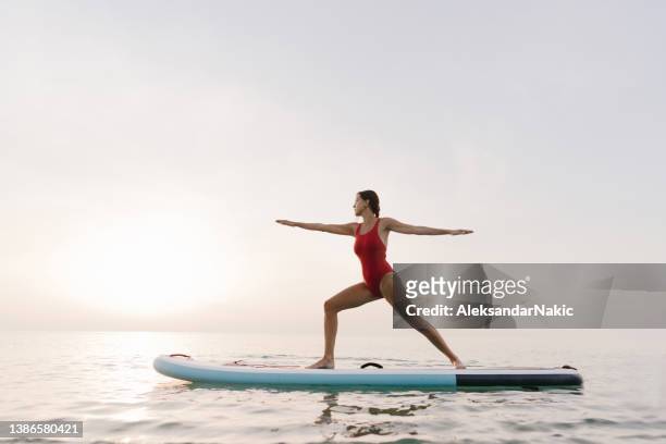 practicing yoga on a paddle board - practioners enjoy serenity of paddleboard yoga stockfoto's en -beelden