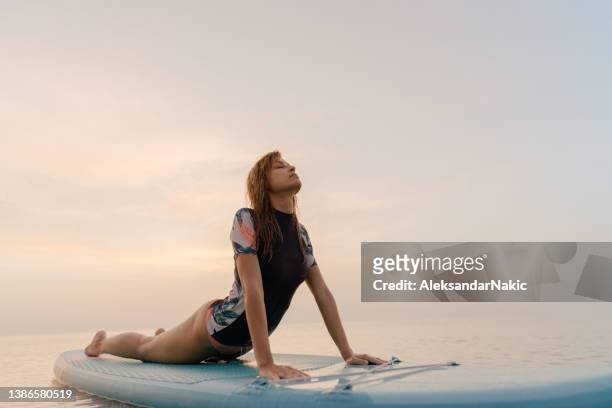 practicing yoga on a paddle board - paddleboard stockfoto's en -beelden