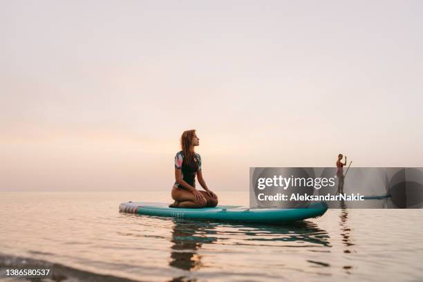 girlfriends stand-up paddling together - sup stockfoto's en -beelden