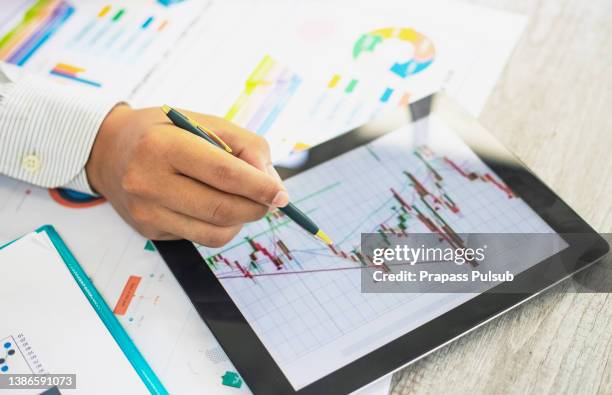 analyzing statistical business reports on  tablet - shareholder foto e immagini stock