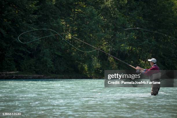 mature asian man fly fishing in river, british columbia, canada - fishing line stock pictures, royalty-free photos & images