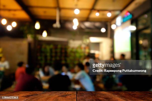 wood table top with blur of people in coffee shop or restaurant, nightclub, pub on background. - horizontal bars foto e immagini stock