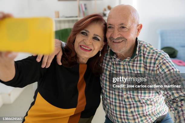 mature couple taking selfie with mobile phone at home - pensioners demonstrate in spain stock pictures, royalty-free photos & images