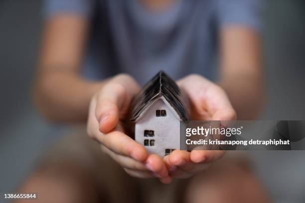 home concept,people, family and home concept - close up of woman and boy holding model house - protection luxe stock-fotos und bilder
