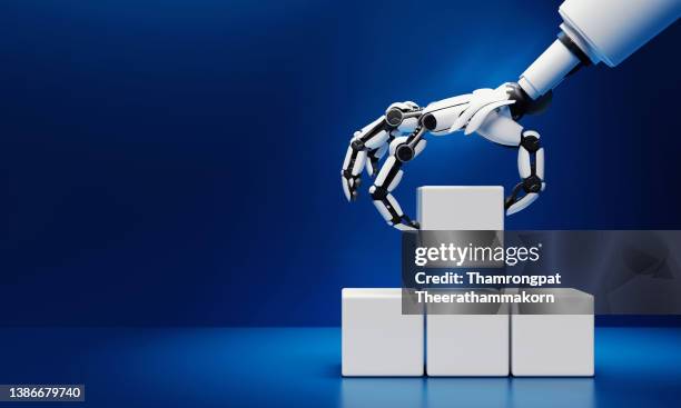 robotics hand grabbing and putting blank white cubic blocks on blue background. innovative industrial technology and artificial intelligence concept. 3d illustration rendering - greif stock-fotos und bilder