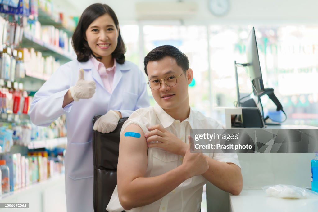 Asian man receive Malaria, Tetanus, Typhoid, Hepatitis vaccine prepare travel jabs with Pharmacist in drug store.