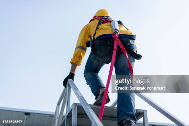 a young mechanic climbs the ladder in the inspection industry. - sicherheitsausrüstung stock-fotos und bilder