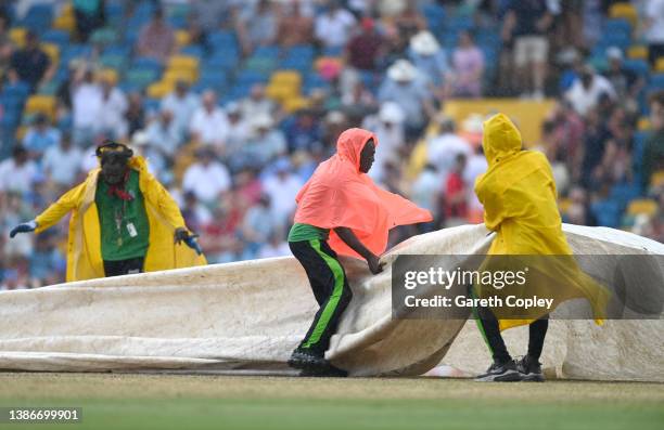 Groundstaff cover the pitch as rain stops play during day five of the 2nd test match between West Indies and England at Kensington Oval on March 20,...