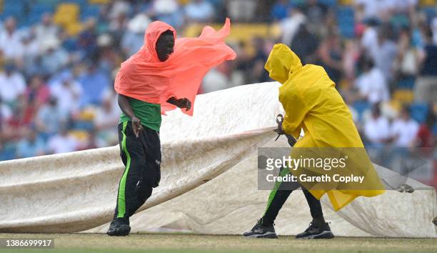 Groundstaff cover the pitch as rain stops play during day five of the 2nd test match between West Indies and England at Kensington Oval on March 20,...