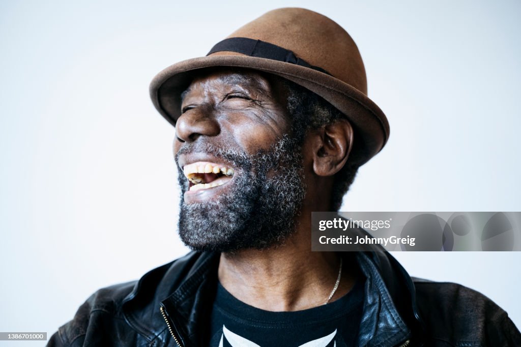Candid portrait of senior Afro-Caribbean black man looking away laughing