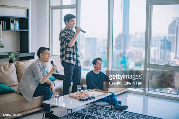 asiatische chinesische männliche freunde genießen karaoke-session zu hause am wochenende essen pizza - room mates male stock-fotos und bilder