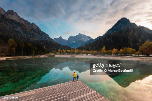 father and son enjoying the view of alpine lake - julianische alpen stock-fotos und bilder