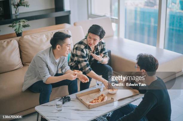 ソーシャルギャザリングアジアの中国人男性は、リビングルームで自宅で彼の友人とファーストフードピザを楽しんでいる - pizza share ストックフォトと画像