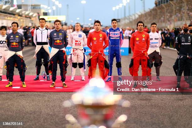 The F1 drivers stand on the grid for the national anthem ahead of the F1 Grand Prix of Bahrain at Bahrain International Circuit on March 20, 2022 in...