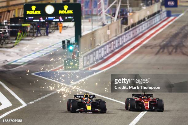 Max Verstappen of the Netherlands driving the Oracle Red Bull Racing RB18 overtakes Charles Leclerc of Monaco driving the Ferrari F1-75 into turn one...