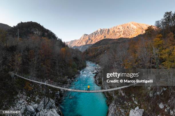 man standing on a suspension bridge above a mountain river - slovenia hiking stock pictures, royalty-free photos & images