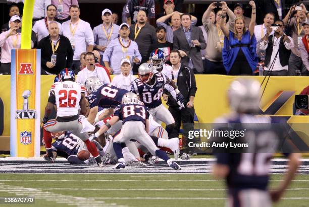 Quarterback Tom Brady of the New England Patriots looks down field as Antrel Rolle of the New York Giants and his teammates break up a hail mary pass...