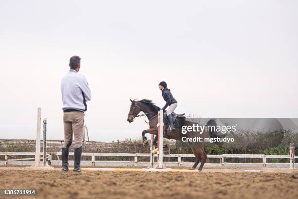 young women learns to jump over obstacles with her rider instructor - hindernisrace paardenrennen stockfoto's en -beelden