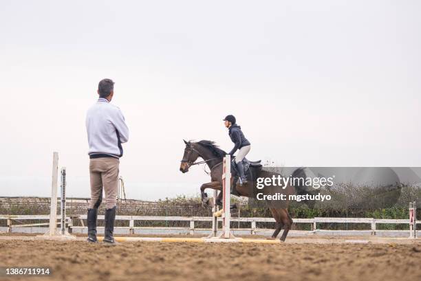 young women learns to jump over obstacles with her rider instructor - equestrian event stock pictures, royalty-free photos & images