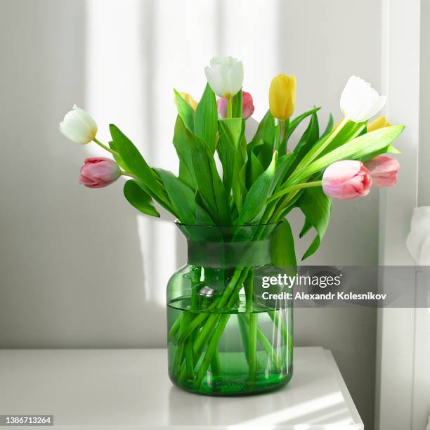 multi-colored tulips in vase on the bedside table in the bedroom near the bed - flowers vase ストックフォトと画像