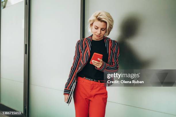 young woman leaning on wall with smart phone and laptop. - black suit close up stock pictures, royalty-free photos & images