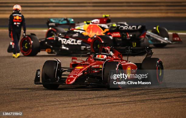 Charles Leclerc of Monaco driving the Ferrari F1-75 ahead of Sergio Perez of Mexico and Oracle Red Bull Racing walking from his car during the F1...