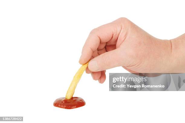 closeup of mans hand dipping french fry in ketchup - tomato sauce stock pictures, royalty-free photos & images